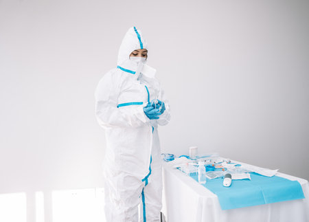 Medic wearing protective uniform and mask standing in hospital and working with medical tools during pandemic ofの写真素材
