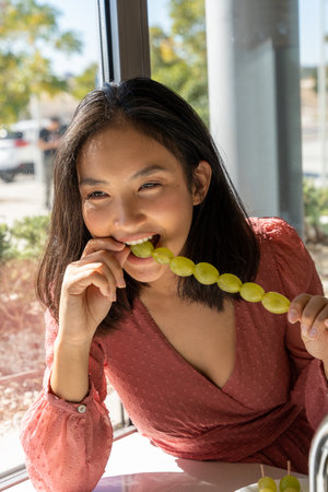 woman swallow a grape in her mouth, tasting its flavor, close-up vertical viewの写真素材