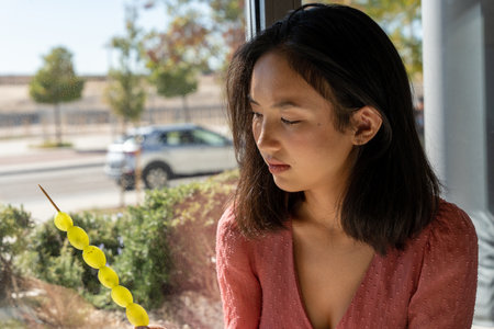 woman observing carefully a skewer of grapes, close-up horizontal viewの写真素材