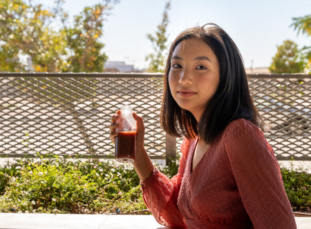 woman posing facing the camera with a glass of healthy drink in her hand on a sunny day, close-up horizontal viewの写真素材