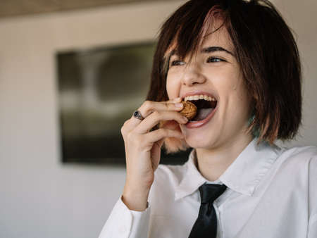 woman laughing while trying to bite a walnut with her mouth, horizontal blurred backgroundの写真素材