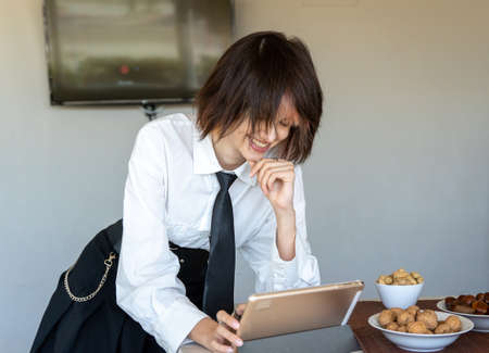 smiling woman in work clothes smiling using a tablet, nuts on the side, plain white backgroundの写真素材