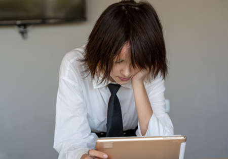 front view of a girl in a shirt and tie looking at information on a tablet, horizontal plain...