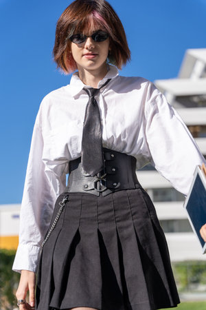 close-up view of woman in shirt, tie and skirt walking forward, vertical portrait, view from belowの写真素材
