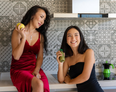 two women enjoying their time having a snack in the kitchen, well-dressed in formal clothesの写真素材