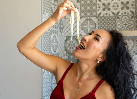 woman testing spaghetti to see if they are already cooked, head back, horizontal backgroundの写真素材