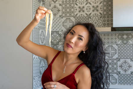 portrait of a woman holding spaghetti with her hand up, looking at the camera, horizontal cut-out viewの写真素材