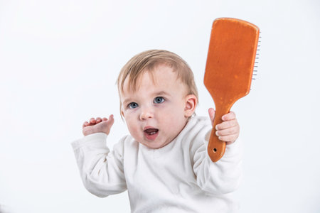 Stock studio photo with a white background of a baby with a comb in his handの写真素材