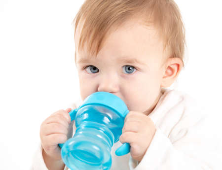 Stock studio photo with a white background of a baby drinking water from a canteen with handles.の写真素材