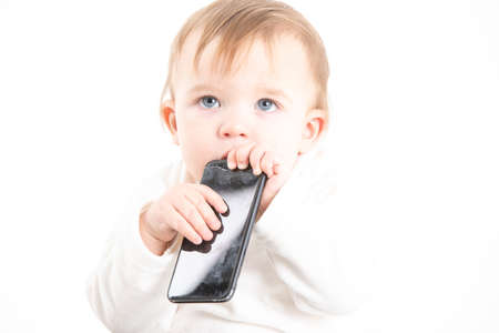 Stock studio photo with the white background of a baby's face with a mobile in his mouthの写真素材