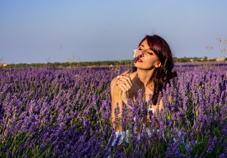 Woman smelling a flower in a lavender flower field. Nature concept.の写真素材
