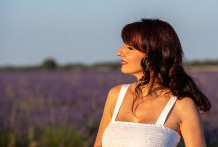 Close up view of a woman looking away while standing outdoors in the nature in lavender field.の写真素材