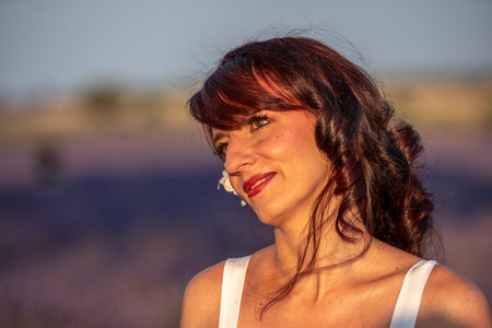Close up view of a woman looking away while standing outdoors in the nature in lavender field.の写真素材