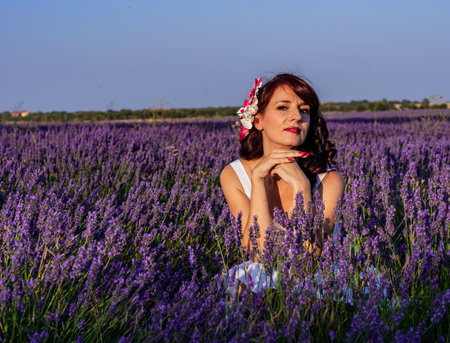 Woman looking at camera while posing outdoors in a lavender flower field. Nature concept.の写真素材