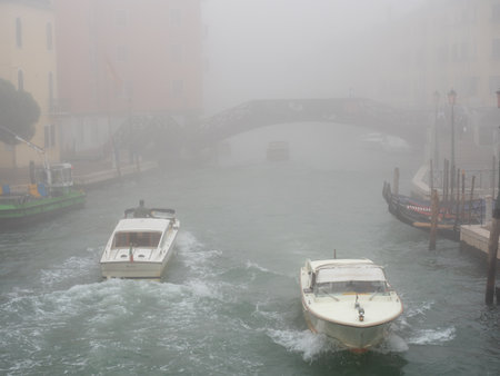 November 1, 2022 - Venice, Italy: Boats sailing in a canal in Venice on a foggy day. Tourism concept.の写真素材