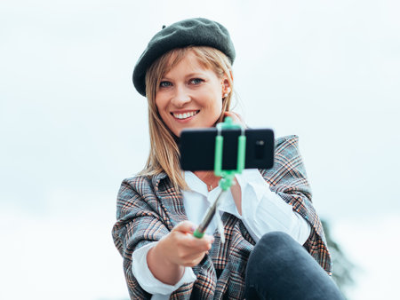 Caucasian girl with French hat takes pictures of herself with a selfie stickの写真素材