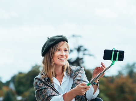 Caucasian girl with French hat takes pictures of herself with a selfie stickの写真素材