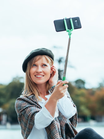 Caucasian girl with French hat takes pictures of herself with a selfie stickの写真素材