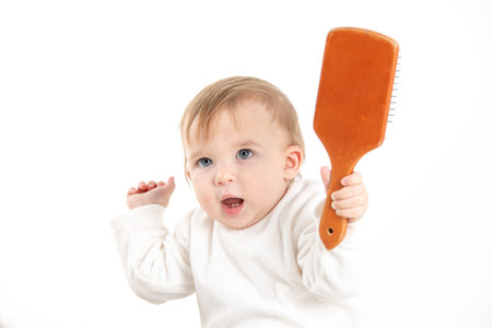 Stock studio photo with a white background of a baby with a comb in his handの写真素材