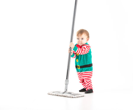 Stock studio photo with white background of a baby disguised as an elf playing with a mopの写真素材
