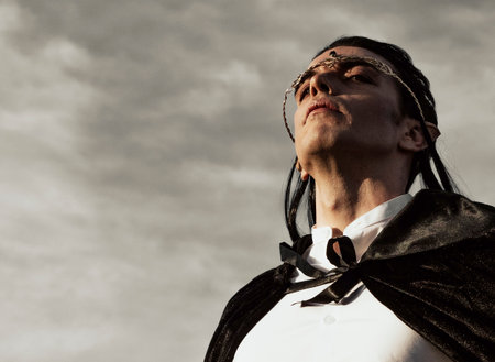 Brown-haired man with elf ears, tiara on head and black cape, looks forwardの写真素材