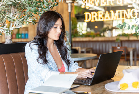 Woman typing on laptop while working sitting in a coffee shop. Technology, business and freelance concept.の写真素材