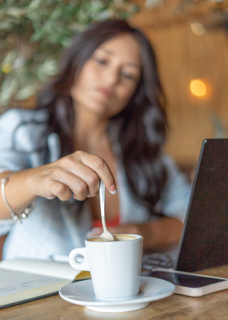 Woman working online with a laptop while sitting in a coffee shop.の写真素材