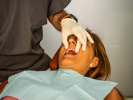 Dentist opens the mouth of his patient and begins to revise the interior helped by his instrumentsの写真素材