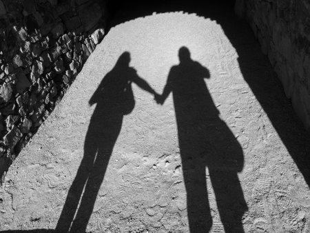 Black and white photograph of the shadow of a couple holding hands. Love concept.の写真素材