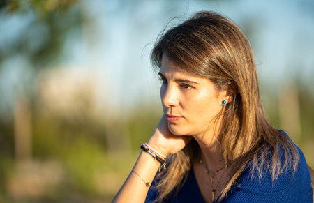 Close up view of a woman with thoughtful face while relaxing outdoors in the nature at daytime.の写真素材