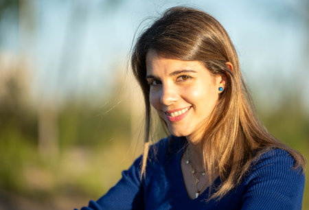 Close-up of a woman looking at camera and smiling while enjoying outdoors in nature.
