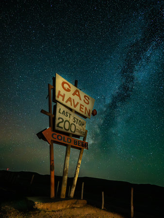 An old gas station sign stands alone in the desert beneath a bright, star-filled Milky Way sky.の写真素材