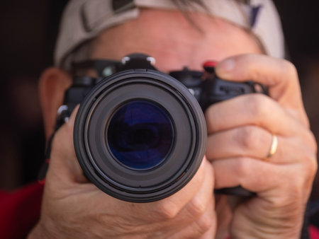 Close-up shot of a photographer aiming at a camera, with the lens dominating the frame.の写真素材