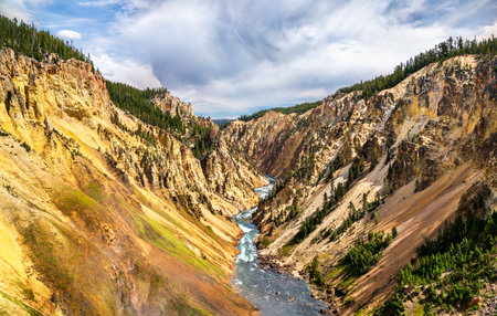 Colorful cliffs and winding river carve through the dramatic Grand Canyon of the Yellowstone, showcasing geothermal hues and rugged terrain in Yellowstone National Park, Wyoming, United Statesの写真素材