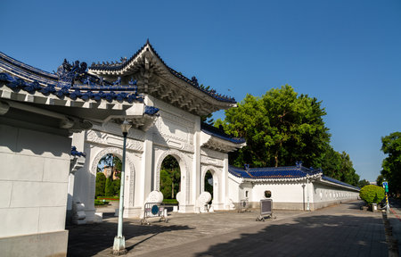 Crisp morning view in Taipei, Taiwan, shows a triple-arched white gate with deep-blue tiled roofs and dragon ornaments marking a side entrance to Liberty Square at Chiang Kai Shek Memorial Hallの写真素材