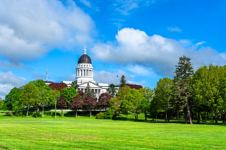 In Augusta, United States, the Maine State House dome peeks above leafy Capitol Park with a bright spring lawns under a vivid blue skyの写真素材