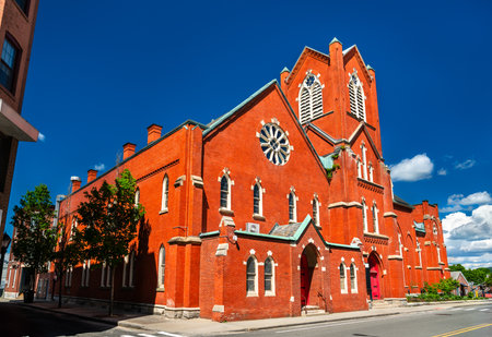 The red brick First United Methodist Church in Pittsfield, Massachusetts, United States, displays Gothic Revival arches, rose window and corner tower beneath a vivid summer sky.の写真素材