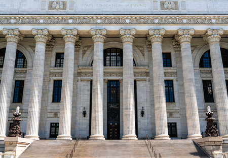 Massive Corinthian columns line the marble facade of the New York State Education Building in Albany, United States, their white stone glowing in bright summer sun above sweeping entry stepsの写真素材