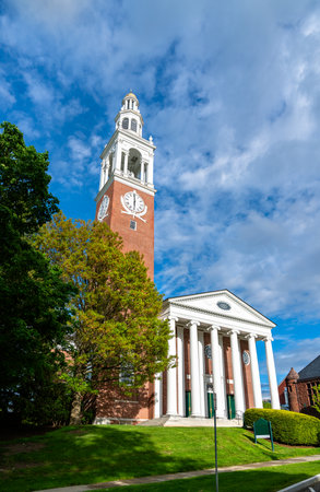 Ira Allen Chapel at the University of Vermont in Burlington, United States, rises with a brick clock tower and columned portico beneath a vivid blue spring sky.の写真素材
