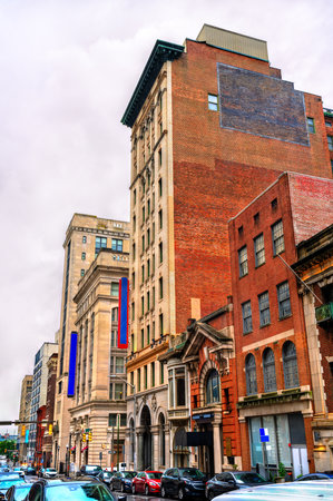 A view of historic architecture along Calvert Street in downtown Baltimore, Maryland, United States. The scene features a mix of brick and stone commercial buildings on an overcast dayの写真素材