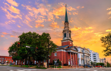 First Baptist Church of Denver, Colorado, at sunset. The historic brick church and its steeple are lit by warm golden light under a dramatic, colorful skyの写真素材