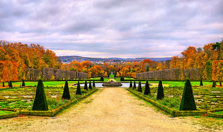 Autumn view of the formal gardens at Chateau de Champs-sur-Marne near Paris in France. Colorful fall foliage and sculpted topiaries line the path leading to a fountainの写真素材