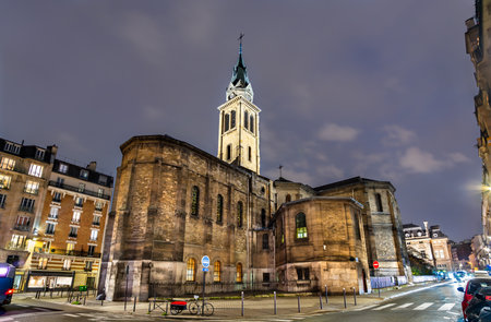 Church of Notre-Dame of Clignancourt in Paris, France. Historic Neo-Romanesque building stands on Place Jules Joffrin under a cloudy night skyの写真素材