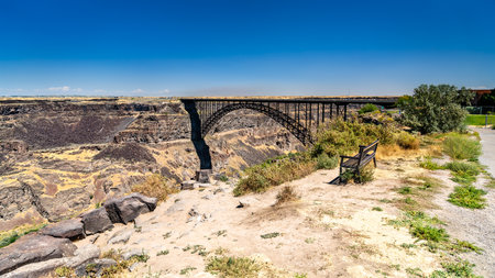 A view of the Perrine Bridge arch in Twin Falls, Idaho. The steel structure spans the deep basalt cliffs of the Snake River Canyon under a clear blue sky. Represents engineering and infrastructureの写真素材