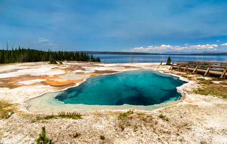 Deep blue Abyss Pool sits near shore of Yellowstone Lake in West Thumb Geyser Basin of Yellowstone National Park, Wyoming. Hot spring features vibrant turquoise water and mineral rim on sunny dayの写真素材