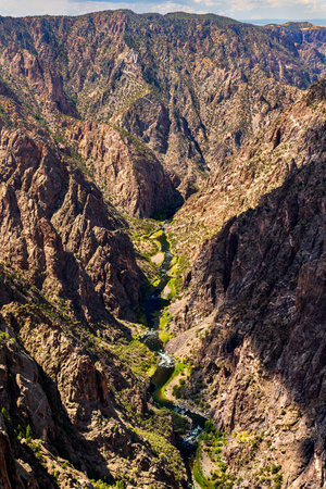 Vertical view looking down at the Gunnison River flowing through the deep, narrow Black Canyon. Steep granite cliffs cast shadows on the waterの写真素材