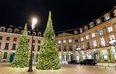 Illuminated Christmas trees stand in Place Vendome at night in Paris, France. Historic square is known for famous luxury boutiques and elegant classical architectureの写真素材