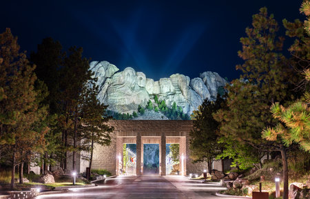 Mount Rushmore National Memorial features illuminated presidents faces at night in South Dakota, USA. Historic sculpture of Washington, Jefferson, Roosevelt, and Lincoln stands above stone entrance pillarsの写真素材