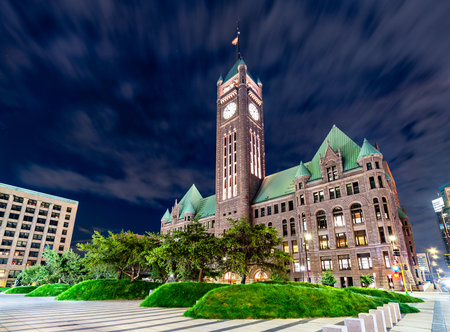 Minneapolis City Hall stands in downtown Minneapolis, USA. Historic Richardsonian Romanesque building features a clock tower and green copper roof at nightの写真素材