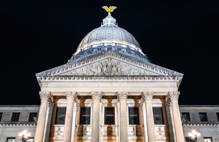 Mississippi State Capitol building in Jackson. Historic Beaux-Arts government architecture features illuminated Corinthian columns and a dome topped with a gold eagle statue at nightの写真素材